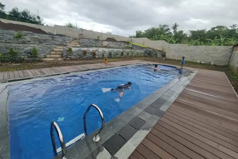 Kolam infinity menghadap taman tropis dengan pepohonan rindang.