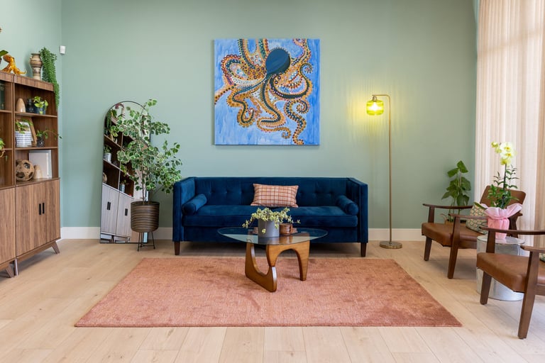 A modern, attractive waiting room with a blue velvet sofa and large art on the walls
