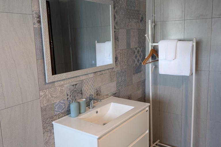 Cottage bathroom with patterned tile wall, large mirror and simple modern fittings