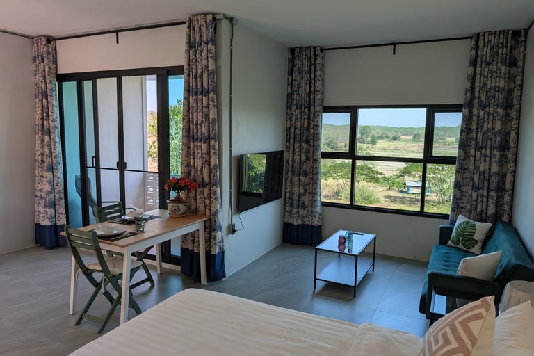 Bright cottage interior with dining table, sofa and wide windows facing the orchard