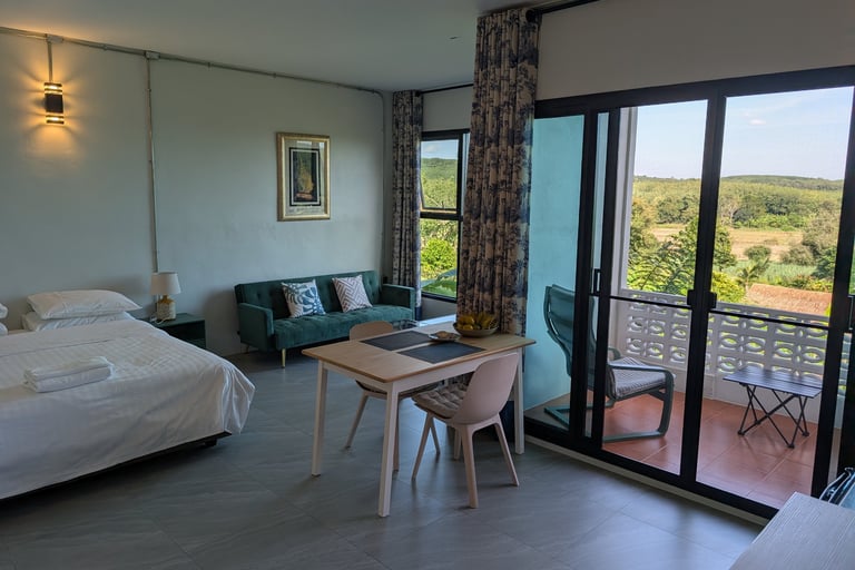 Cottage room with bed, dining area and sliding doors opening to balcony with valley views