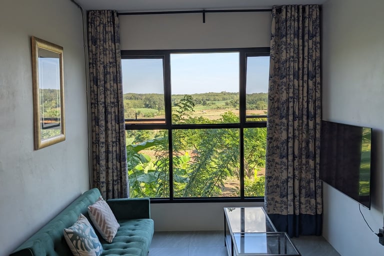 Cottage sitting area with green sofa and large window overlooking orchard and hills