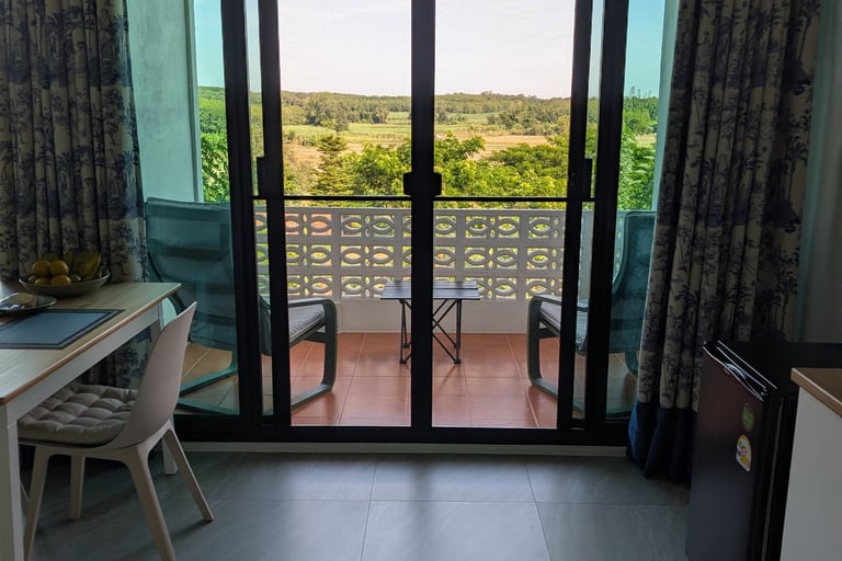 Interior view towards balcony with chairs and wide valley outlook through sliding doors