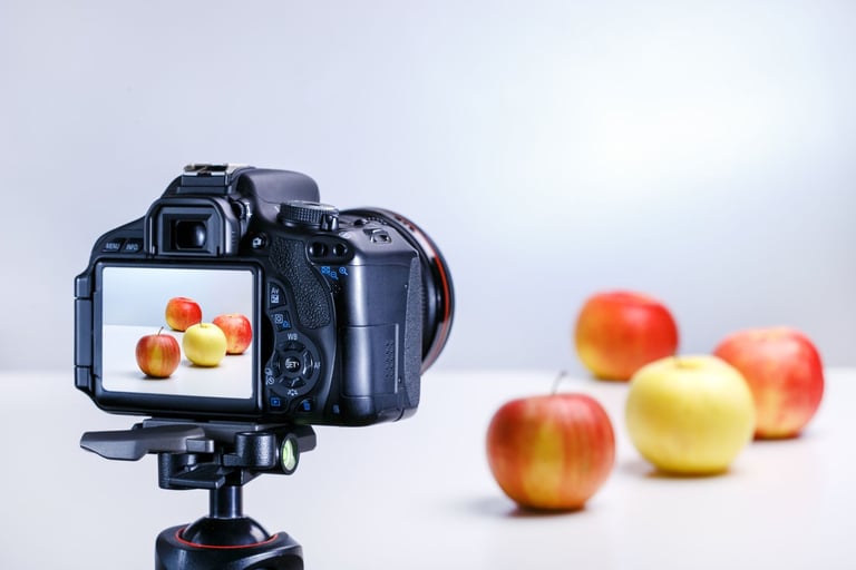 Appareil photo photographiant des pommes sur une table blanche