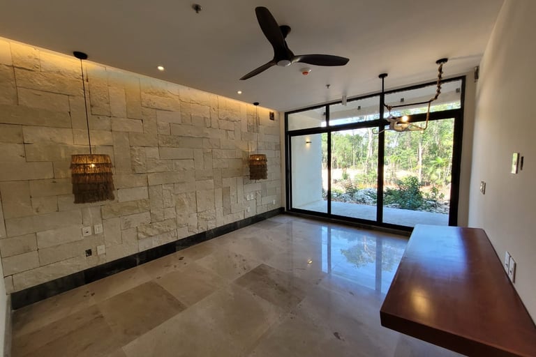 Imagen de espacio al interior de una casa remodelada con muros de piedra natural, pisos de mármol y ventanas de piso a techo