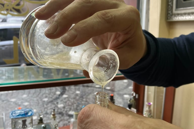 a person is holding a glass of oil based perfume