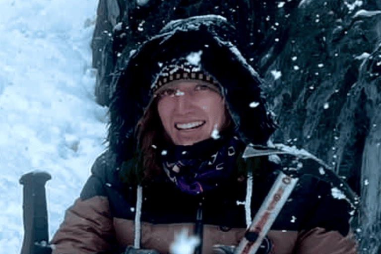 A smiling climber and travel advisor rests during a winter mountain expedition.