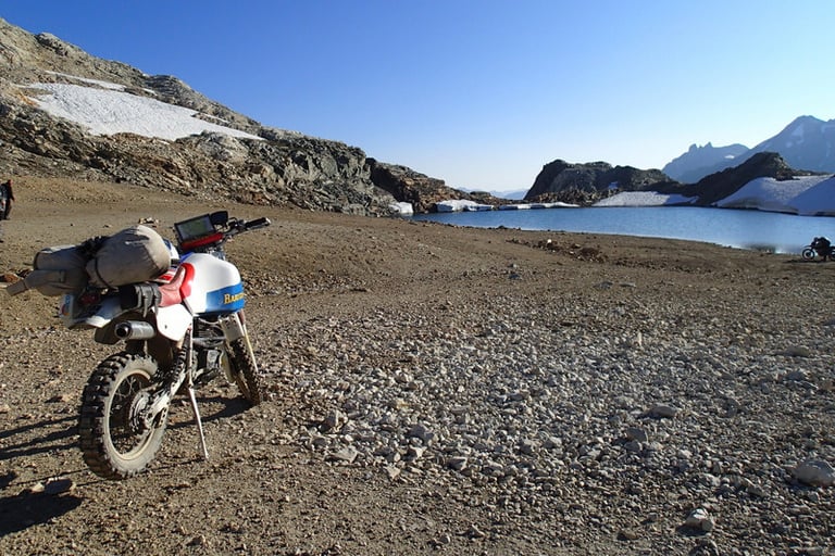 a motorcycle parked on a rocky beach next to a body of water