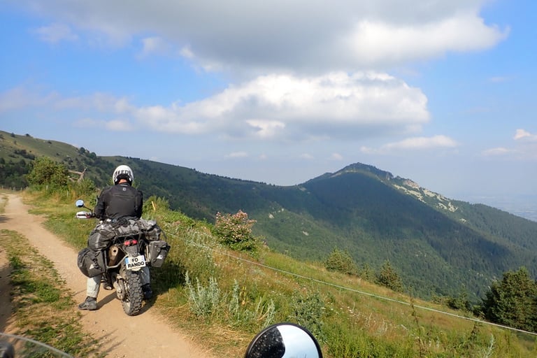 a person riding a motorcycle on a alpin dirt road