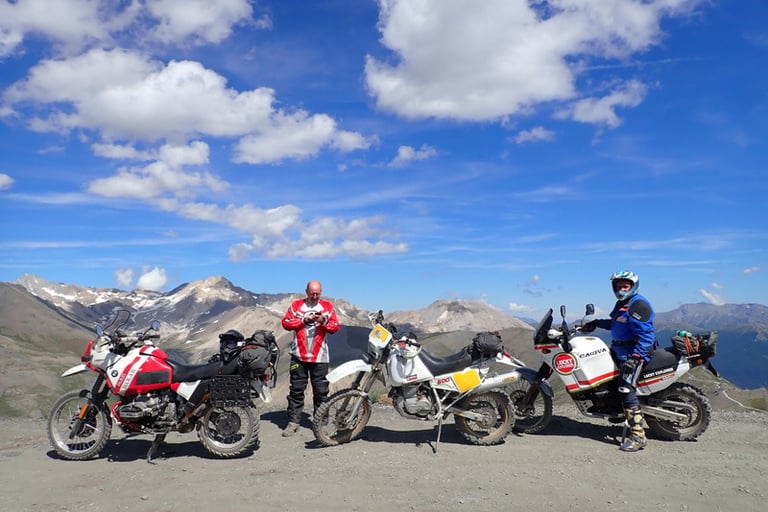 a group of motorcyclists standing in front of a mountain