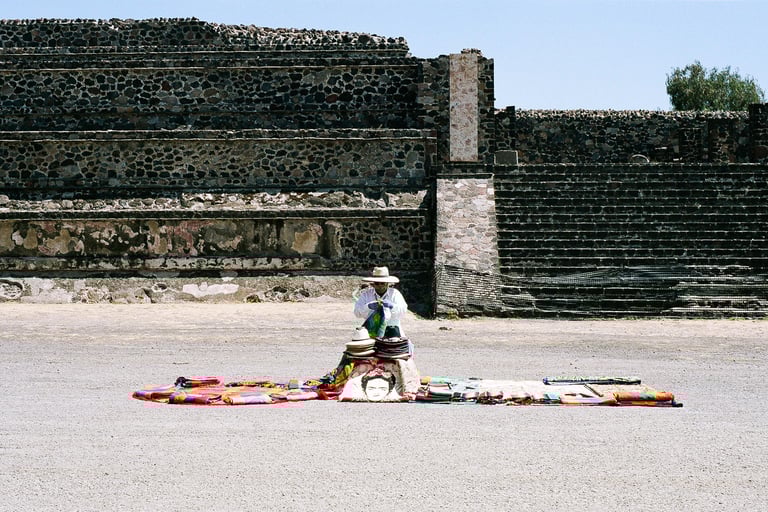 a man in a hat selling hats on a blanket