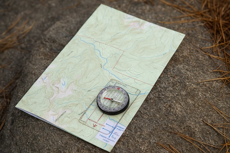 Compass resting on topographic map on forest ground, essential tool for orienteering and survival navigation