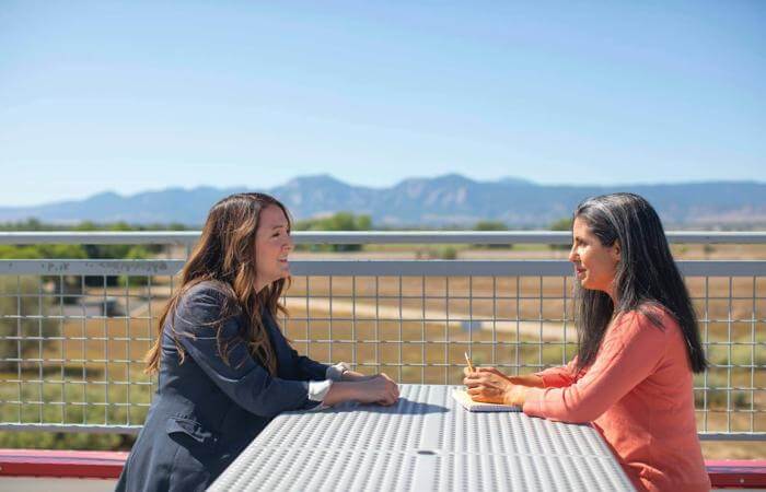 two women sitting at a table having a conversation