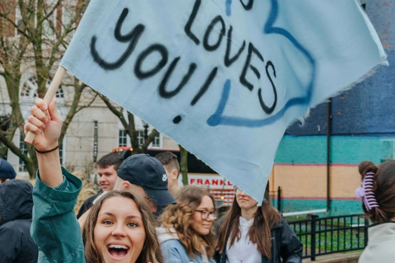 a woman holding a sign that says jesus loves you