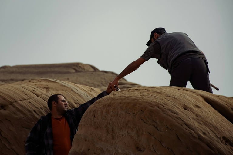 a man and a woman holding hands on a rock formation
