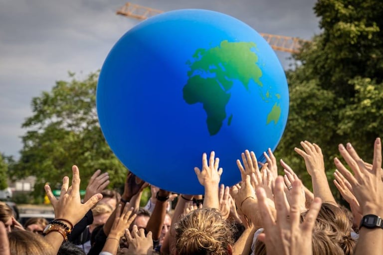 a group of people holding hands up to a blue ball