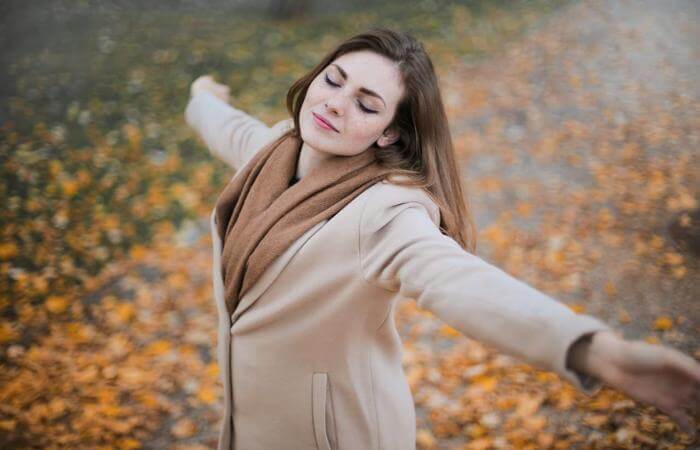 Woman standing with arms open outdoors, expressing freedom, peace, and gratitude.