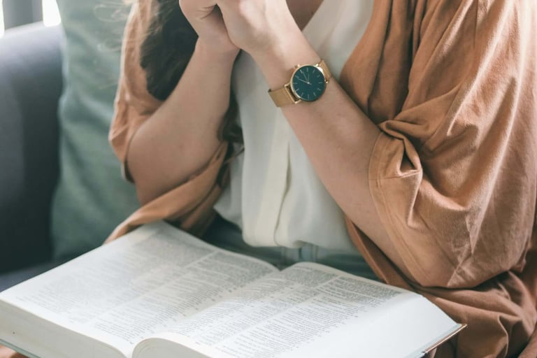 a woman sitting with a bible on her knee and praying
