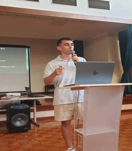 Travis speaking at the podium during a church teaching session.