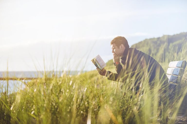 a man sitting on a bench reading a bible