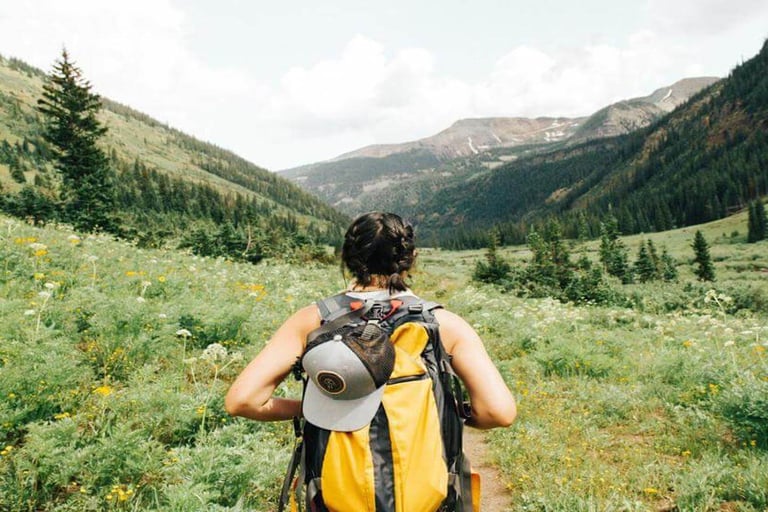 Person hiking through a green mountain valley with a backpack