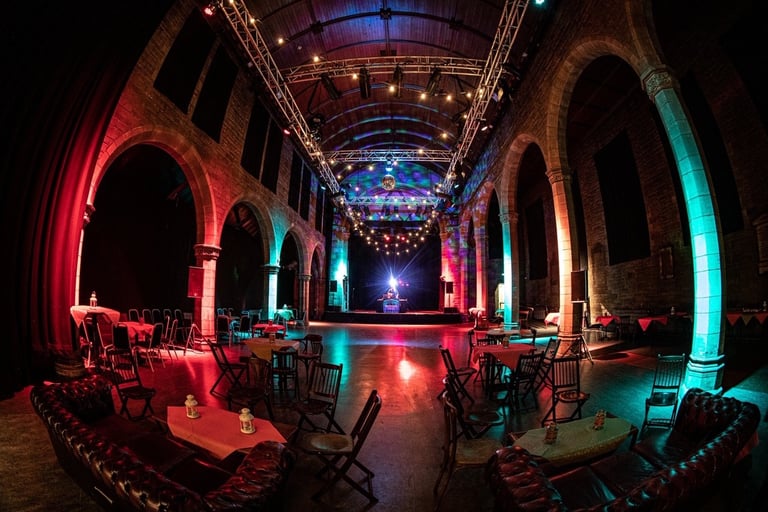 The interior of the Roxy Central, an open space with vaults, red lighting and scattered tables.