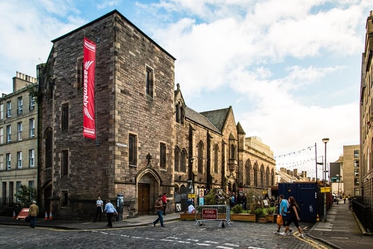 The exterior of the Assembly Roxy Central, a 19c stone building with a 3-story tower.