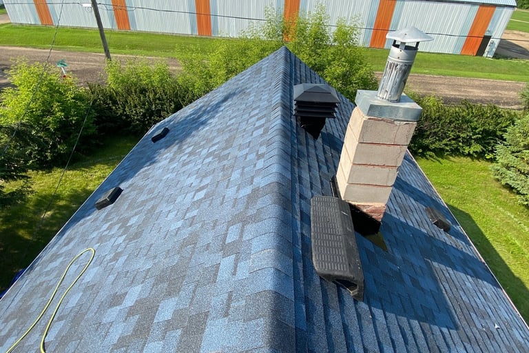 A steep residential roof in Abbotsford with new blue asphalt shingles, and roof vents installed 
