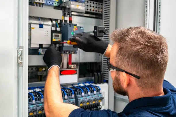 a man in a blue shirt and gloves is working on a machine