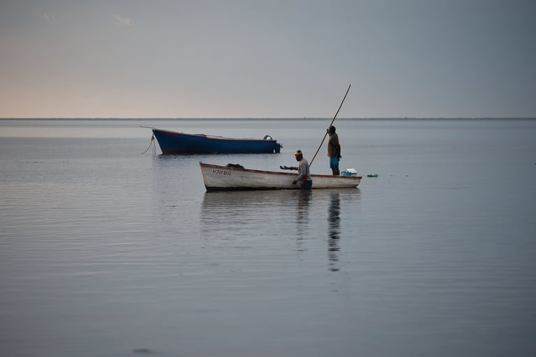 Fishermen at Petite Case Noyale on a traditional wooden boat in calm waters of Mauritius, reflecting the serene early morning
