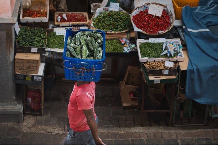 Vendor in Port Louis market carrying a basket of bitter gourds on his head