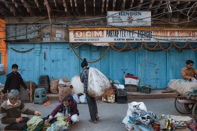 Workers sorting goods and carrying sacks outside closed shops in Old Delhi.