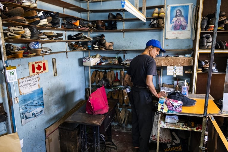 Mauritian cobbler in a small workshop surrounded by shoes, Cape Town Photography Festival 2025