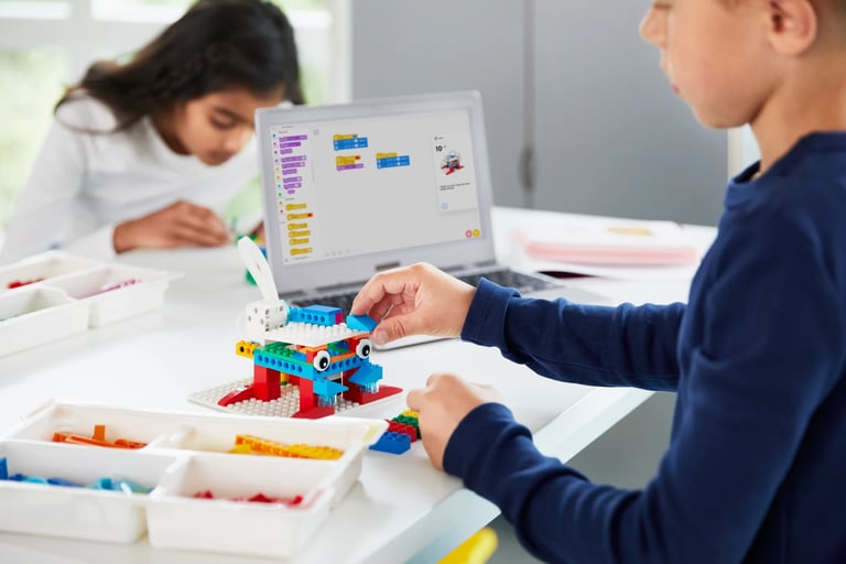 Elementary students build a robot with colorful blocks and program it on a tablet.