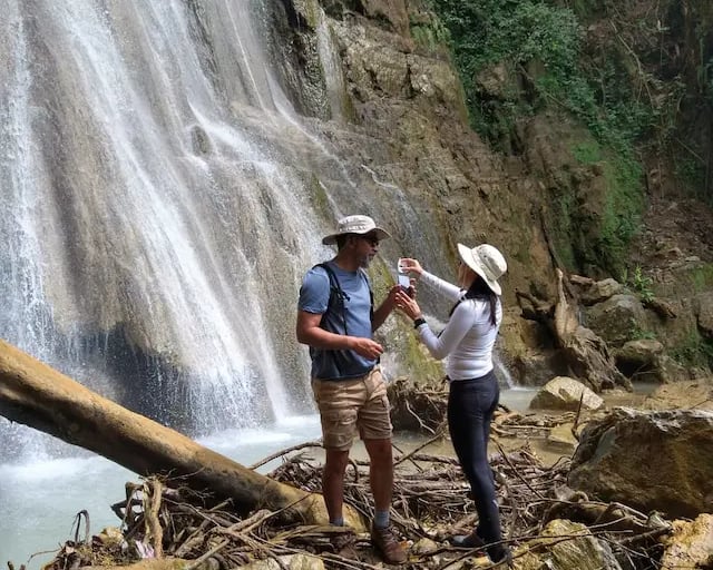 a man and woman standing in front of a waterfall