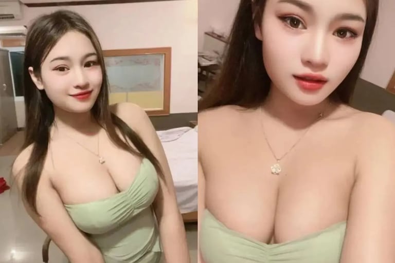 A young Asian woman wearing a light green strapless dress and a gold necklace posing for a selfie.