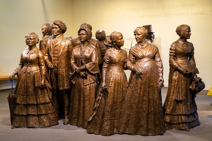 a group of bronze statues of women in dresses