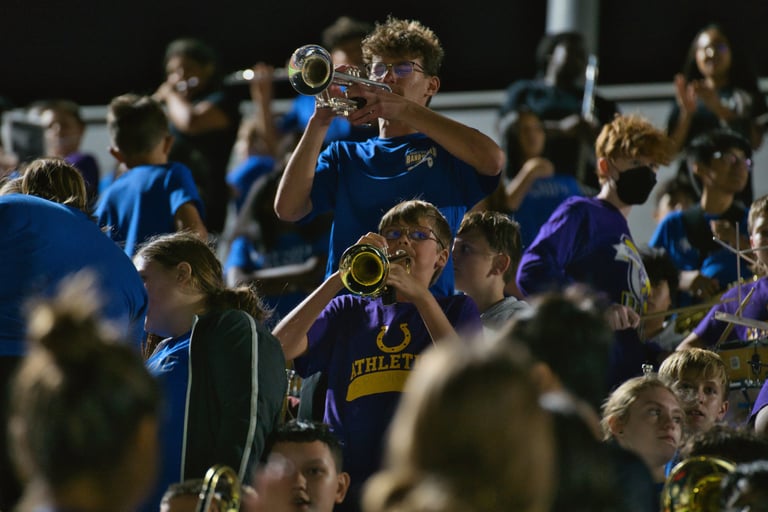 candid photograph of high school band member mentoring a middle school band member