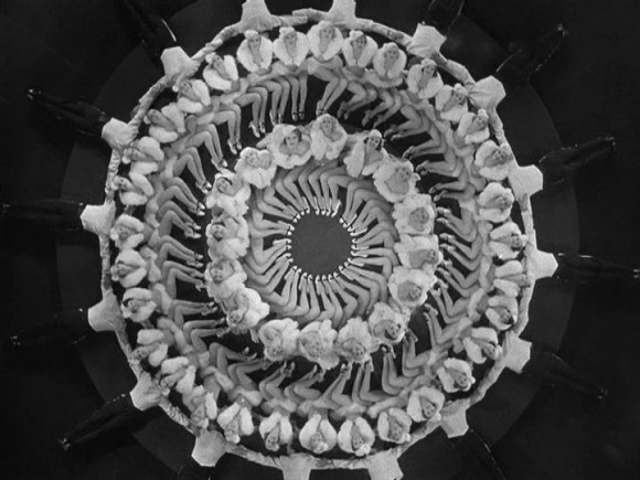 Black‑and‑white overhead shot of Busby Berkeley chorus girls in fur costumes against a dark stage ba