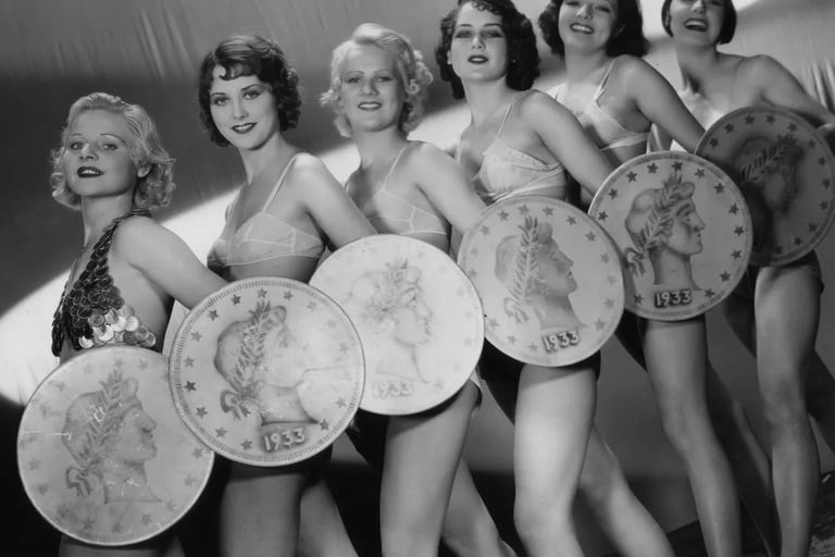Low‑angle shot of six chorus girls with giant coins in Gold Diggers of 1933 “We’re in the Money” mus