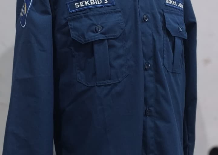 Navy blue custom organizational work shirt on a mannequin with name patches and chest pockets.