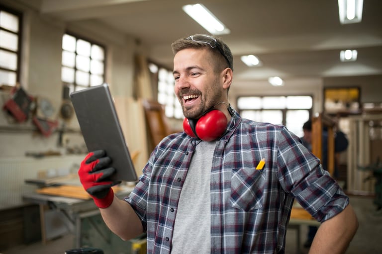 A smiling tradie in a workshop happy with his organised work schedule..