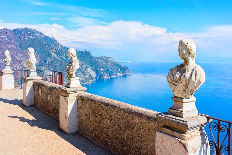 Classical marble busts on the Terrace of Infinity overlooking the blue Amalfi Coast in Ravello, Italy.