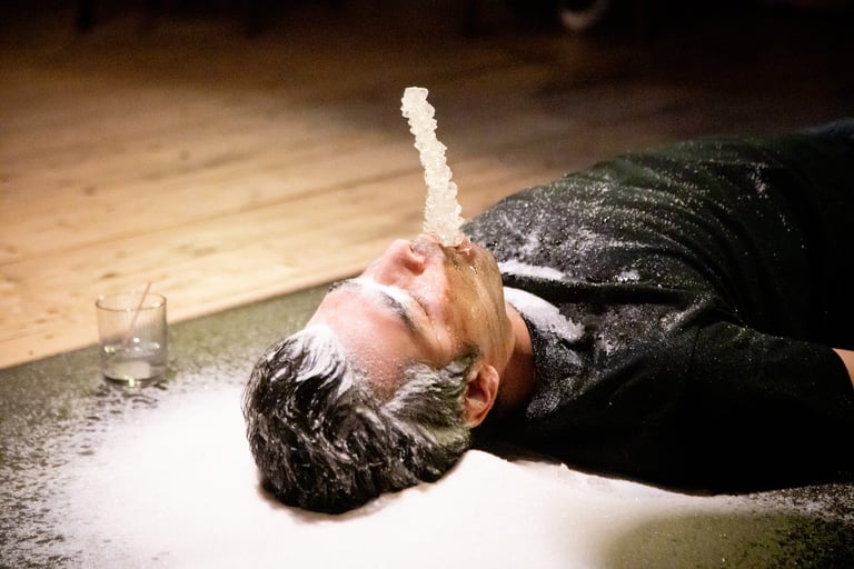 a man is lying on a floor with Sugar candy in the mouth of the artist,