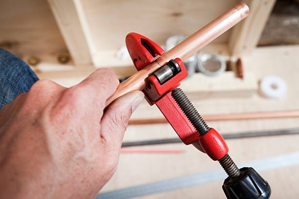 man cutting copper pipe