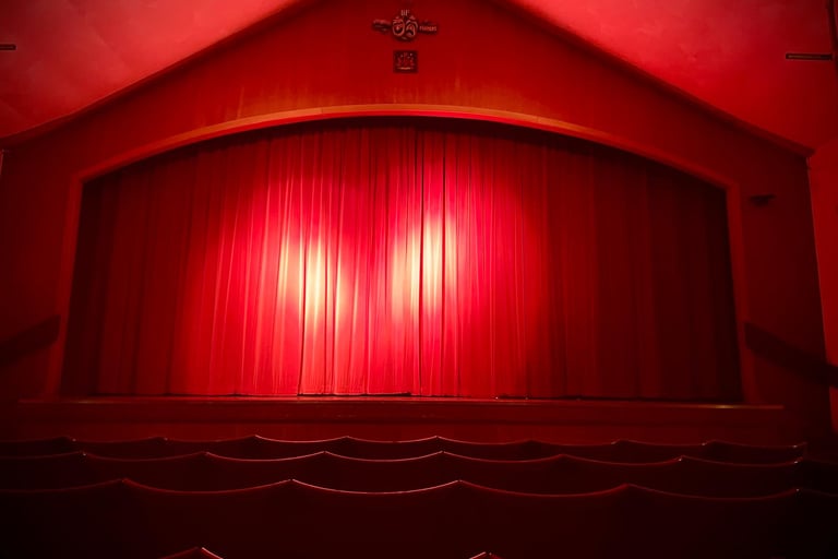A view of a stage with red curtains drawn and two spotlight illuminating them. 