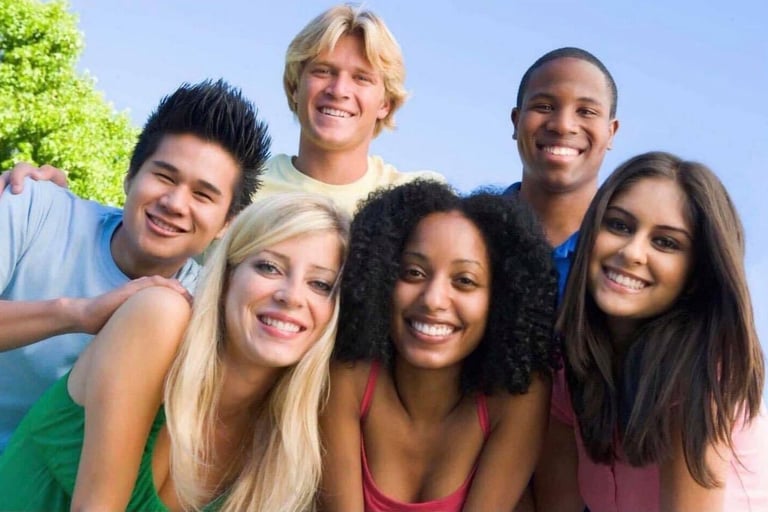 A diverse group of smiling college students and friends outdoors on a sunny day.