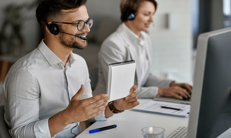Smiling male customer service representative wearing a headset while working in a modern office.