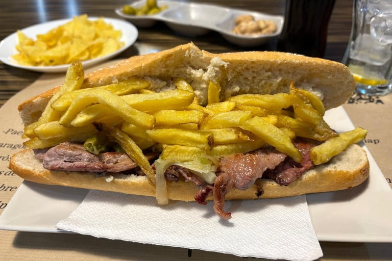 A traditional Spanish steak sandwich topped with crispy golden french fries on a crusty baguette.