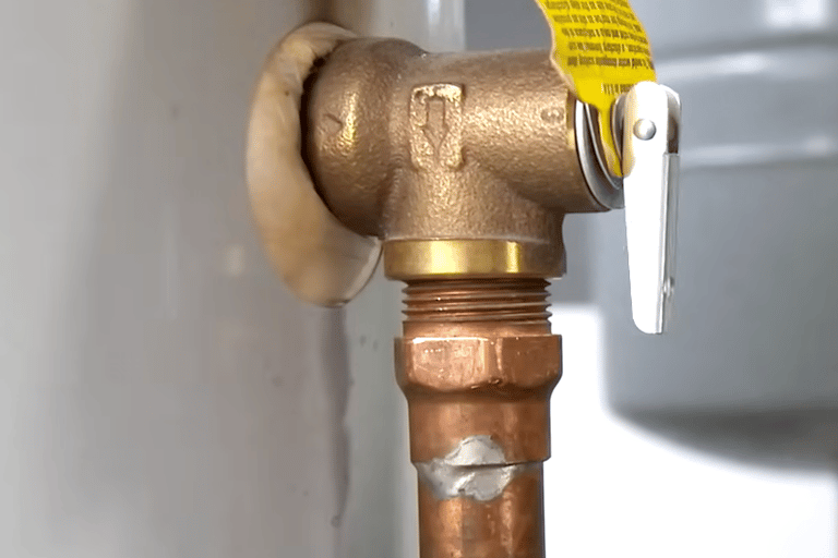 Close-up of a brass temperature and pressure relief valve installed on a residential water heater tank.